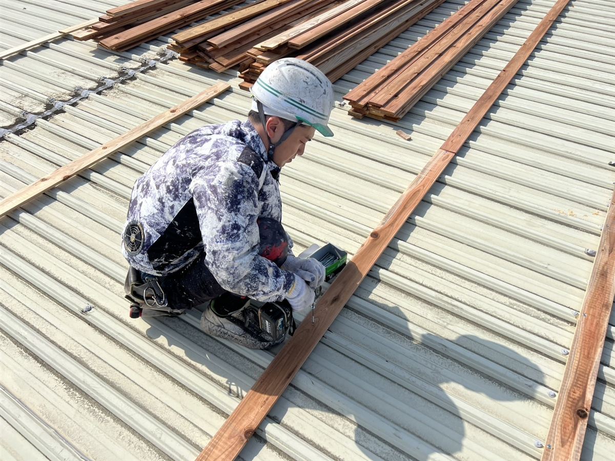 既存屋根の上で木下地を取り付ける作業