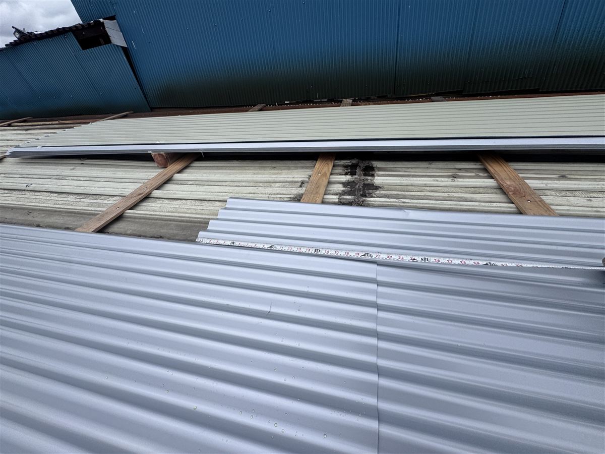 屋根材の重なり寸法をメジャーで確認する工程