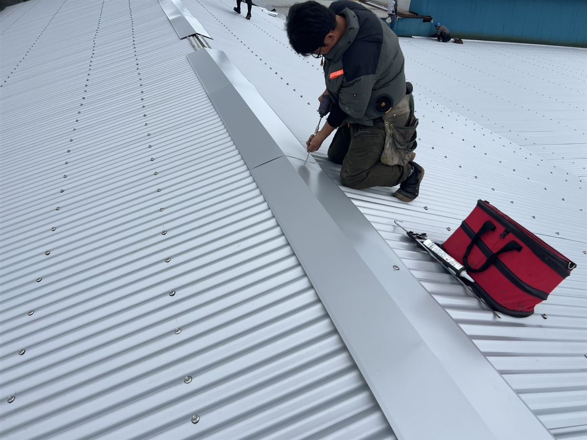 屋根の頂部で棟板金を取り付ける作業