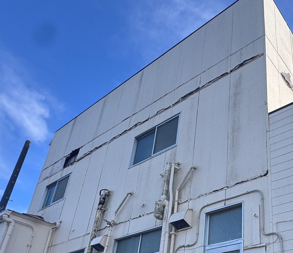 工場外壁の開いた横目地と台風で剥がれた欠損部